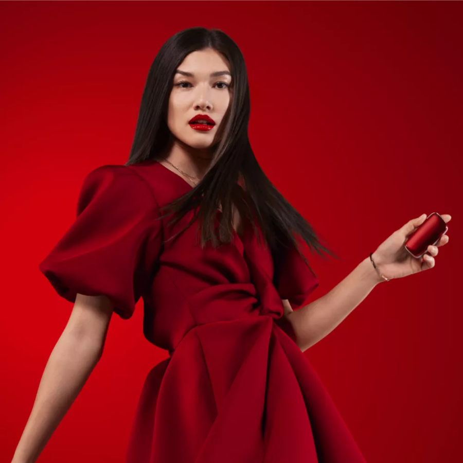 Ragazza che porta un vestito rosso con un dispositivo Ploom X in mano